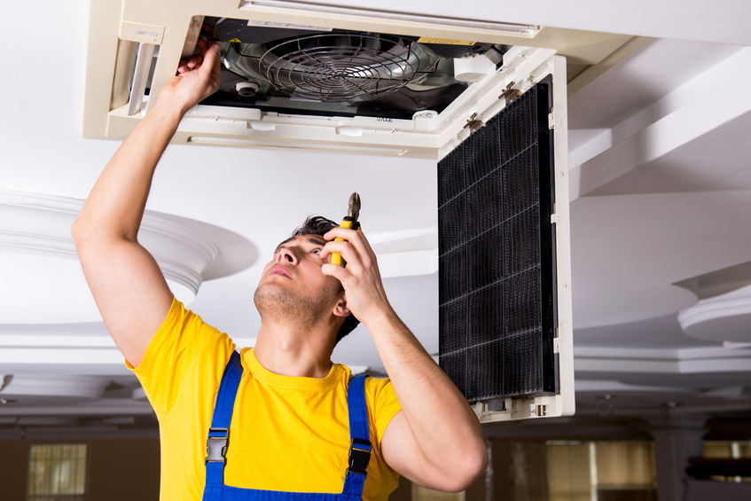 Repairman repairing ceiling air conditioning unit