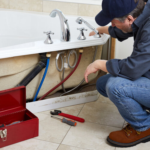 Professional plumber doing plumbing renovation in bathroom.