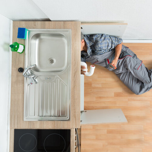 High angle view of plumber working under kitchen sink