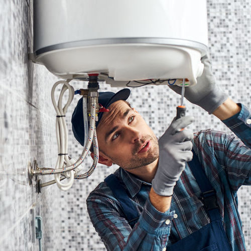 Worker set up electric heating boiler at home. Close-up of young handyman